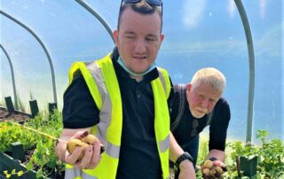 Service user and staff picking potatoes