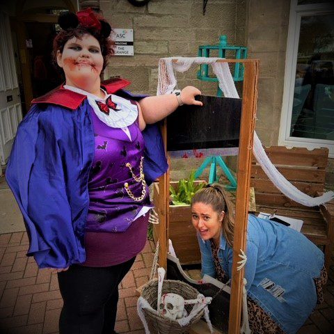 resident dressed in halloween costume with pretend guillotine and Service Manager