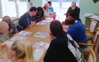 Group of 11 seated at table working on activity sheets